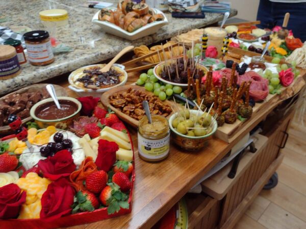 Large spread of food items (incl. fruit, nuts, olives, meats) that can be used for a charcuterie board