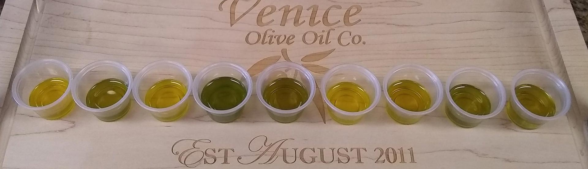 small tasting cups filled with olive oil on a Venice Olive Oil cutting board