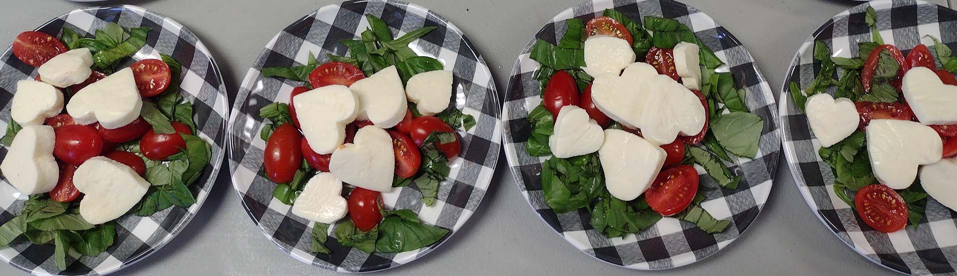 plates with grape tomatoes, heart shaped mozzarella cheese and greens